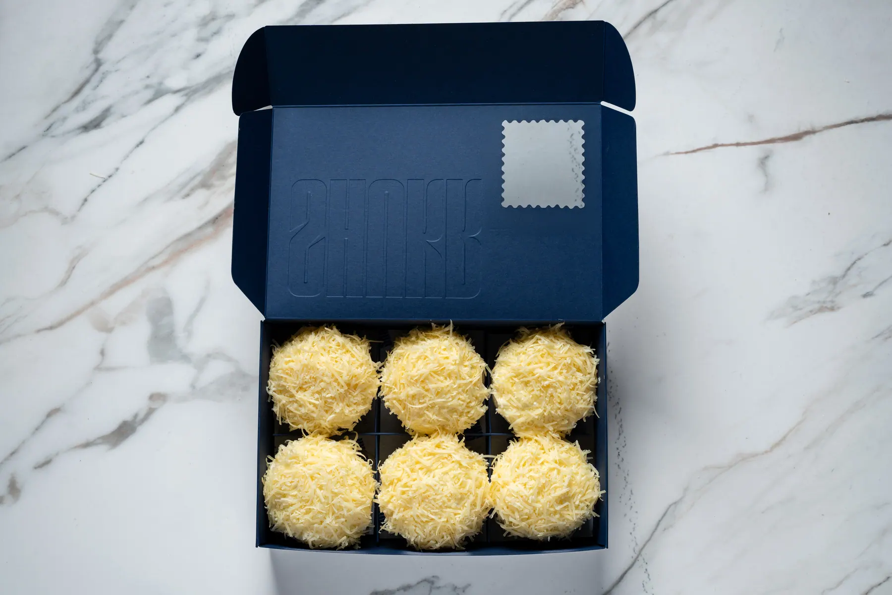 The box of six, open on marble, stamp panel on the lid